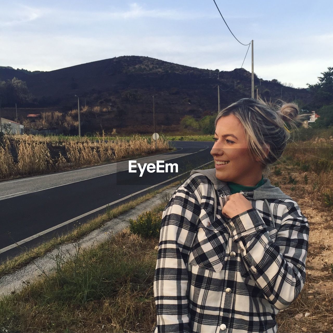 Smiling young woman looking away while standing on landscape