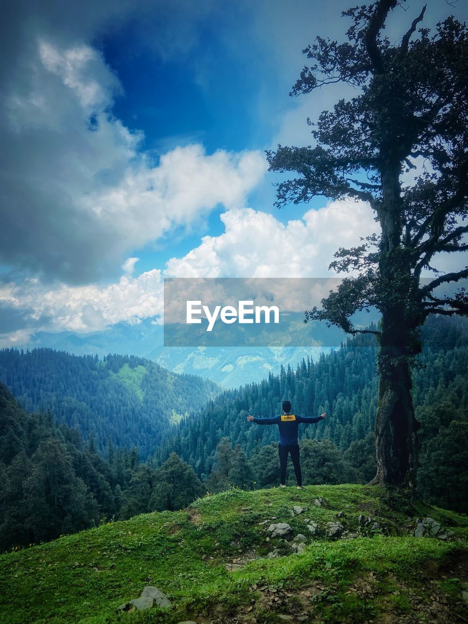 rear view of man standing on mountain against sky