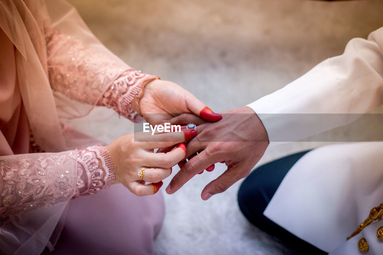 Midsection of bride putting wedding ring in groom finger