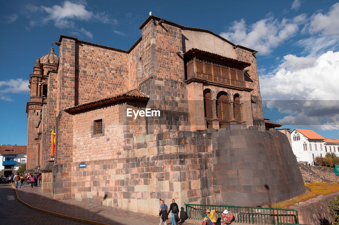 PEOPLE IN FRONT OF HISTORICAL BUILDING AGAINST SKY