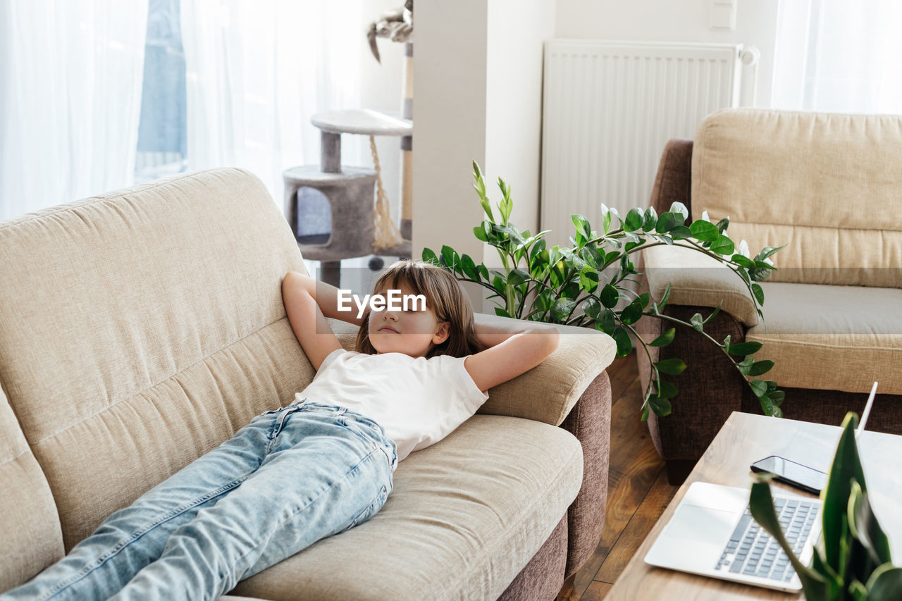 Girl with eyes closed lying on sofa at home