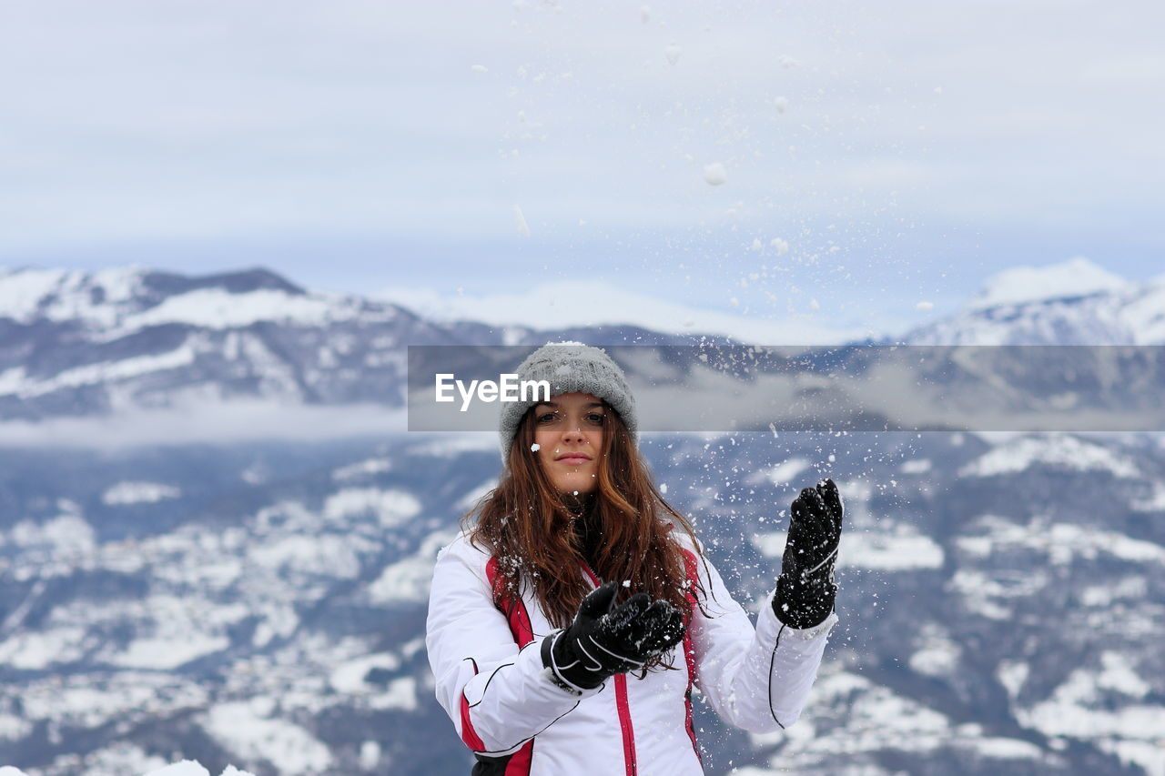 Portrait of woman standing on snowcapped mountains during winter