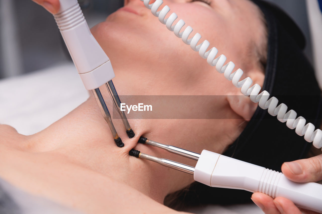 Close-up of a woman receiving an electric neck massage with equipment in a beauty salon. used for