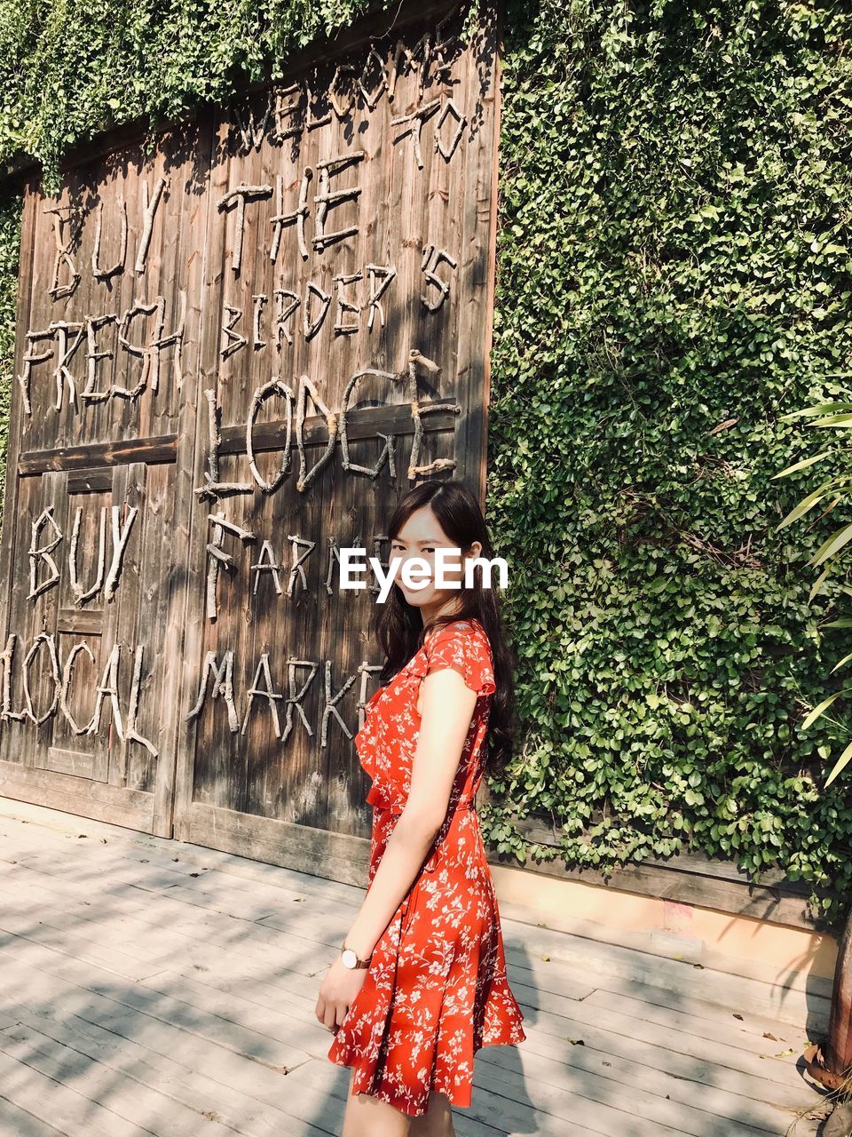 Woman standing against wooden gate