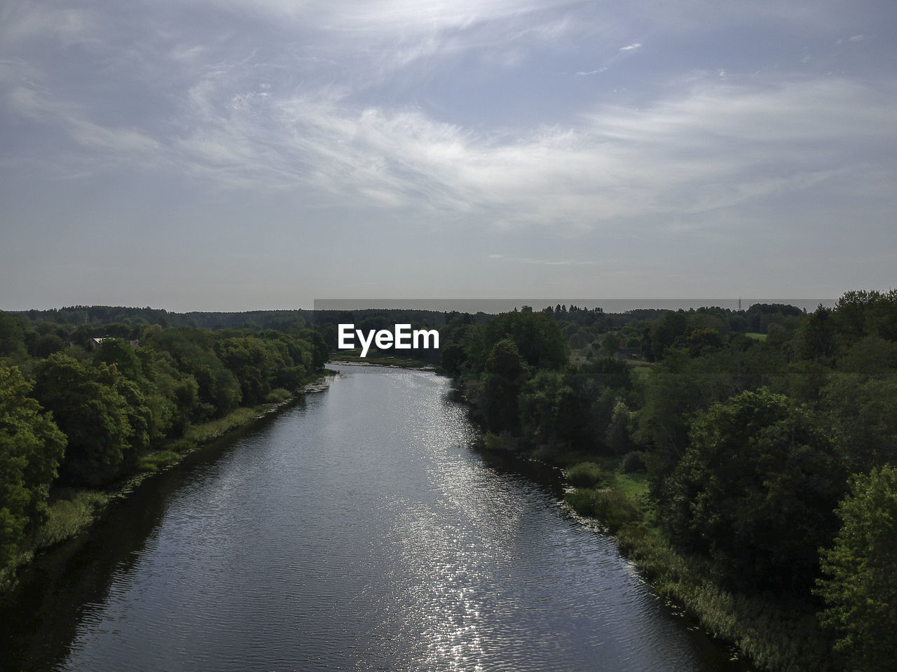 RIVER FLOWING AMIDST TREES AGAINST SKY