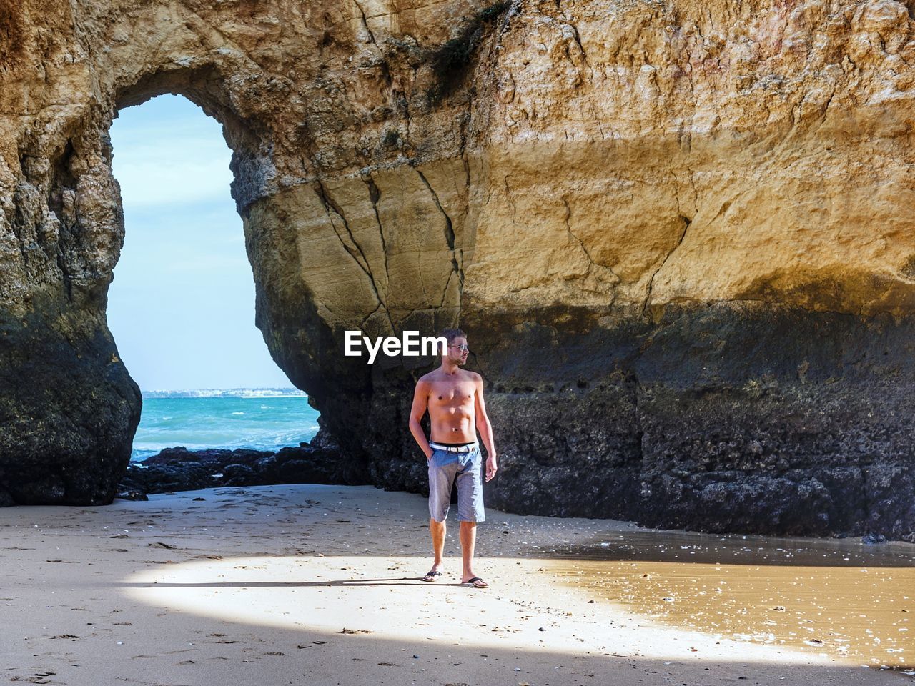 Full length of shirtless man standing on beach