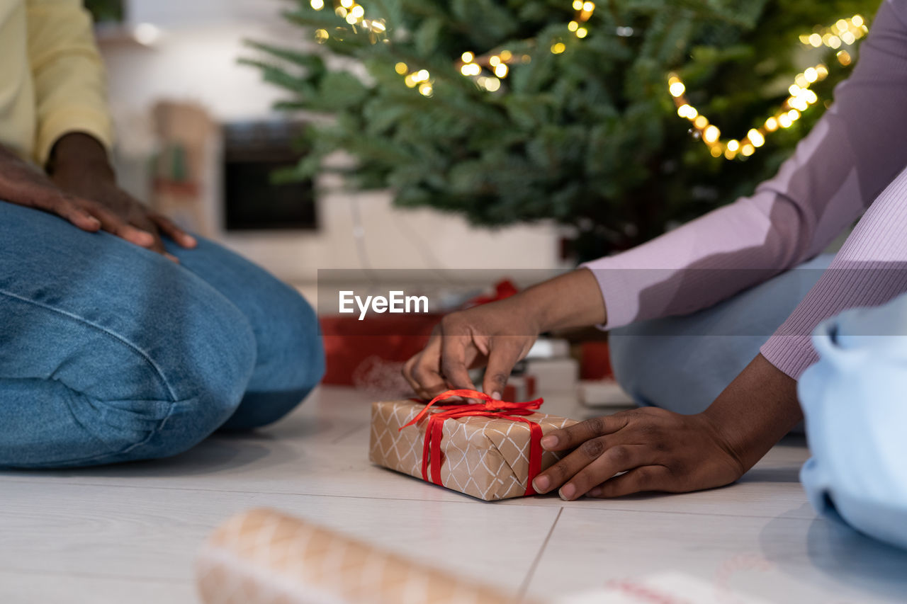 African couple wrapping xmas presents together, preparing for new years eve celebration at home