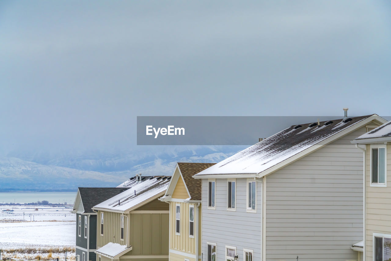 HOUSE BY BUILDING AGAINST SKY