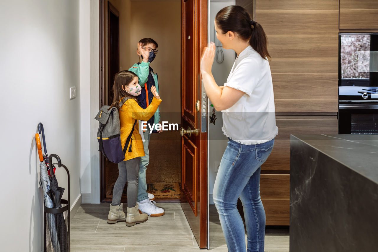 Sibling waving mother while walking through entrance