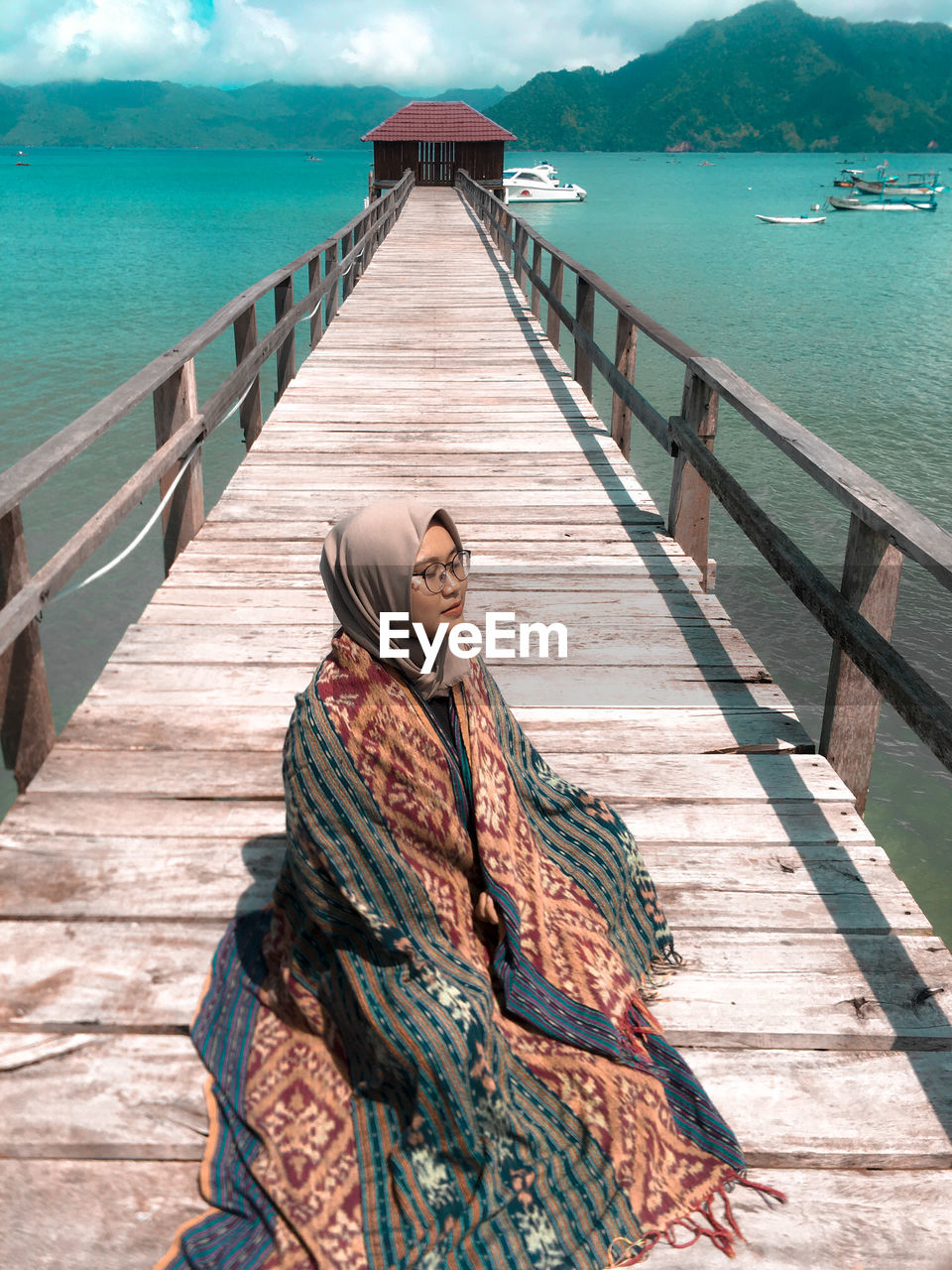 Rear view of woman on pier against sky