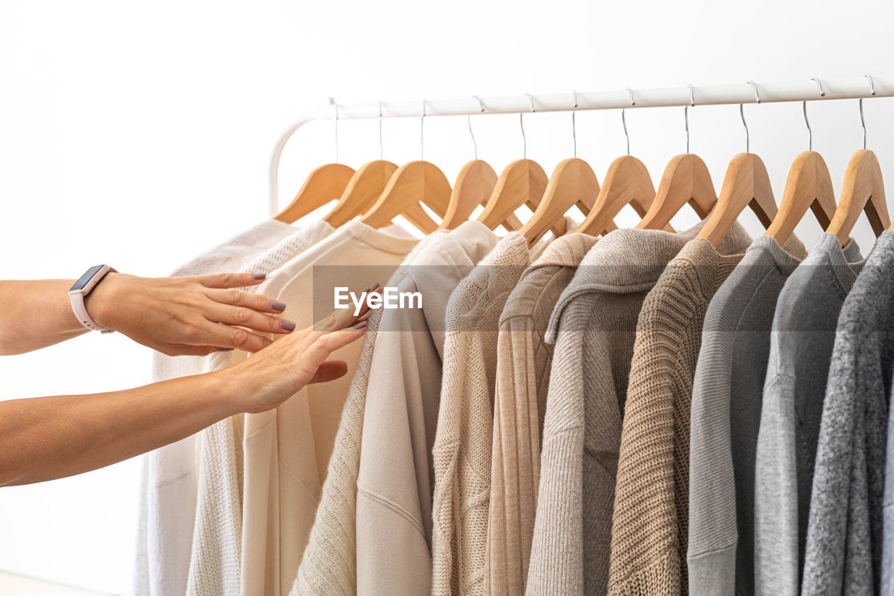 cropped hand of woman with clothes hanging on rack