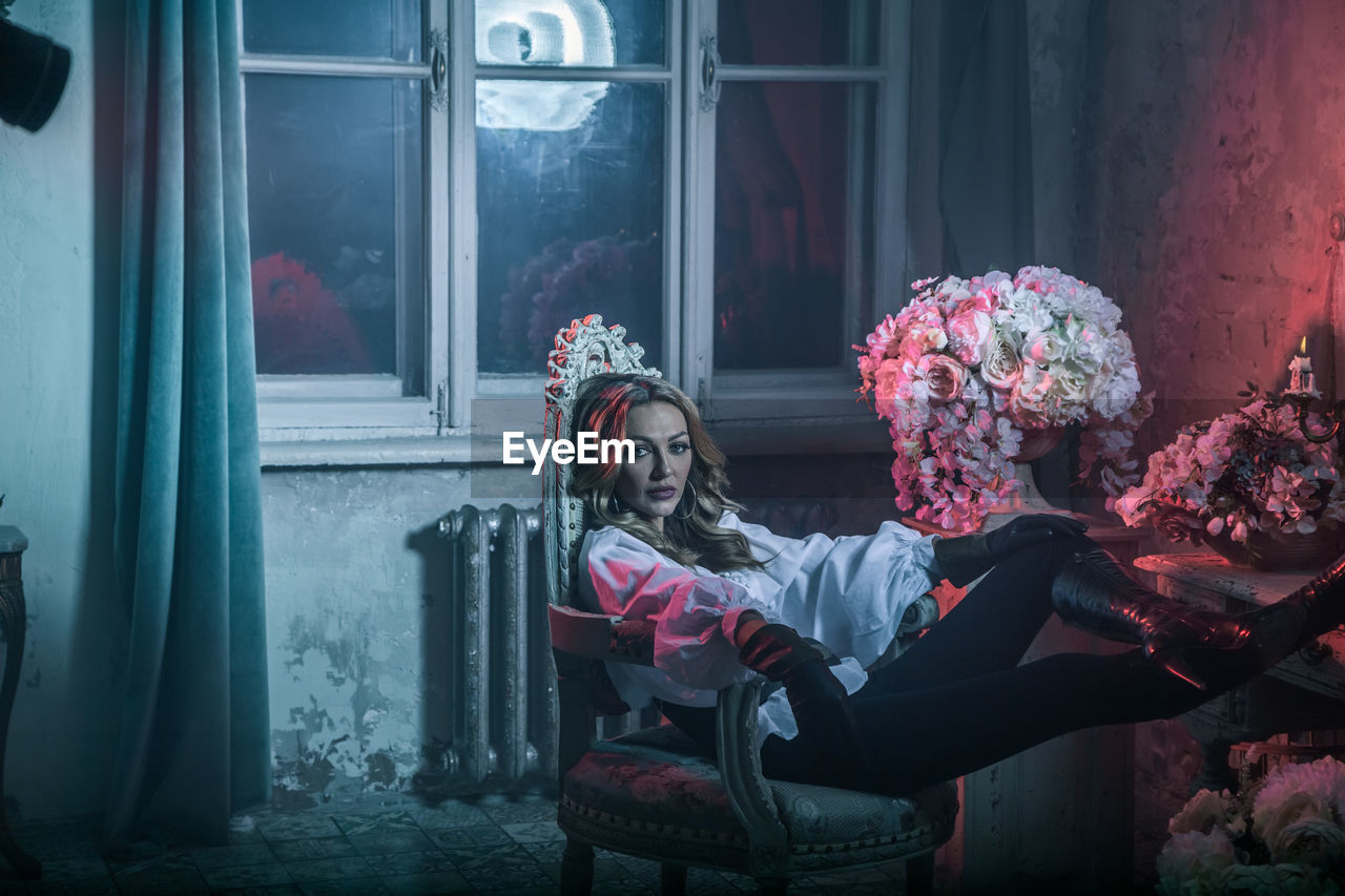 Portrait of woman in costume sitting on chair at home during night