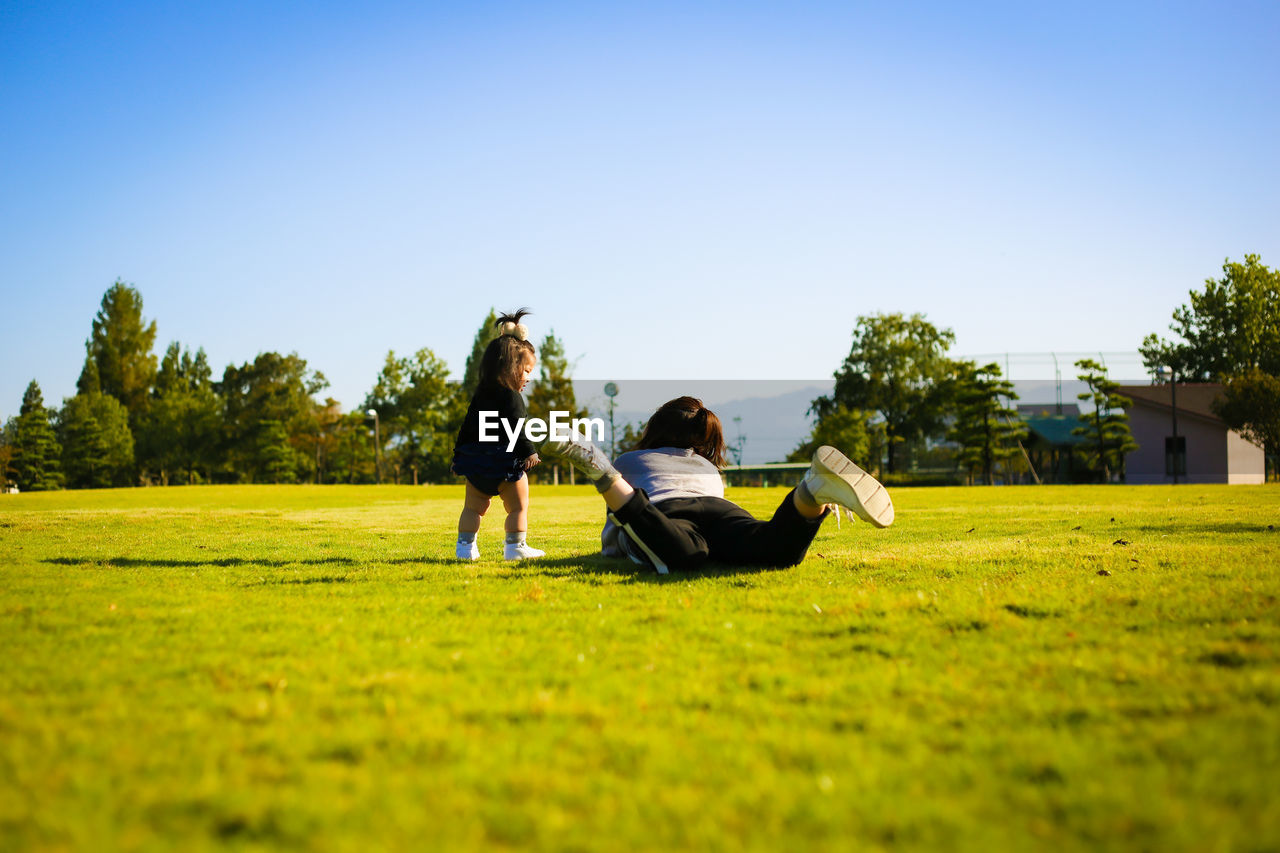 Mother with daughter on grassy land