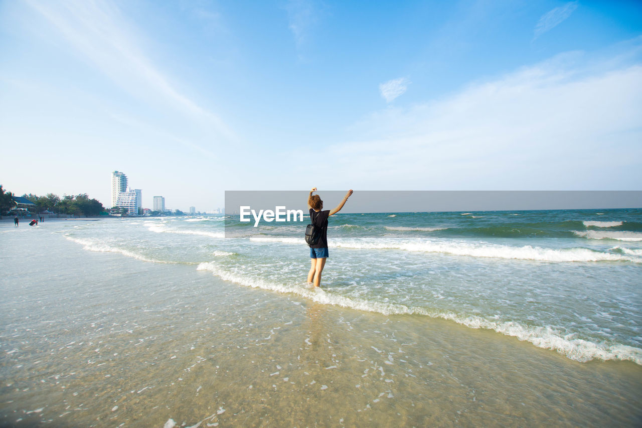Rear view of woman on beach against sky