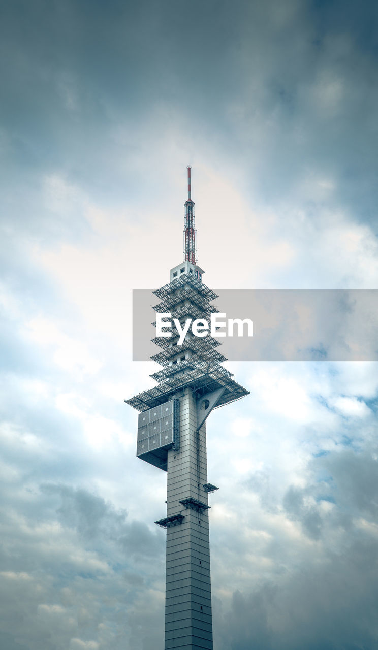 LOW ANGLE VIEW OF COMMUNICATIONS TOWER AND BUILDING AGAINST SKY