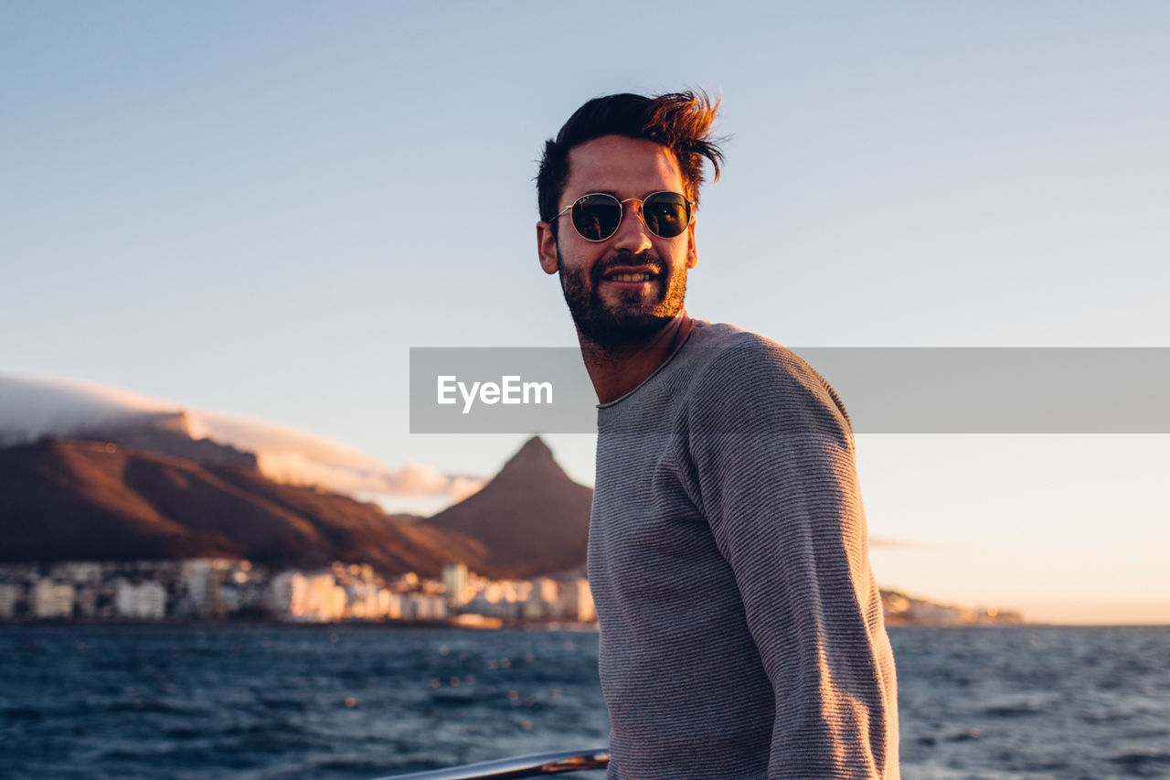 Young man standing in boat on sea against sky