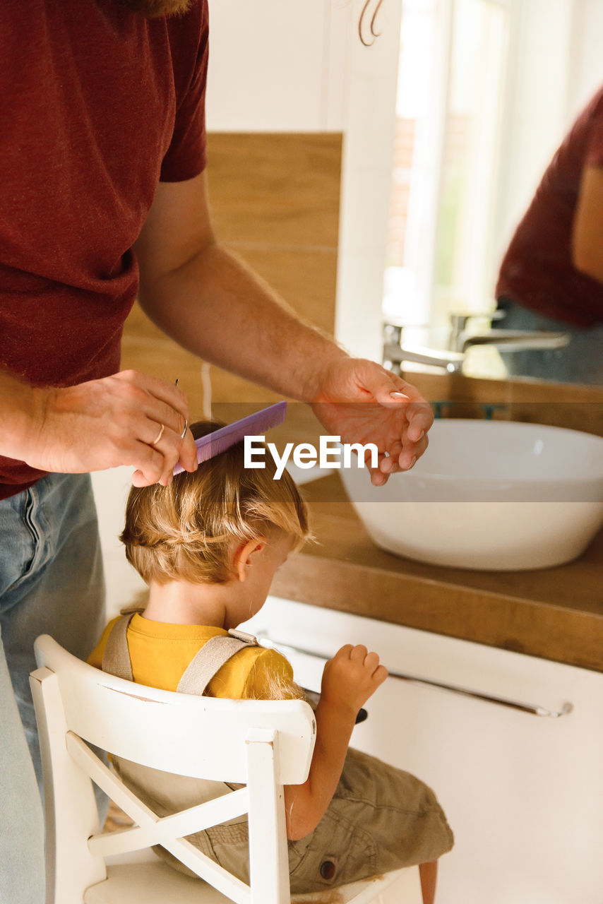 Dad cutting hair to little son