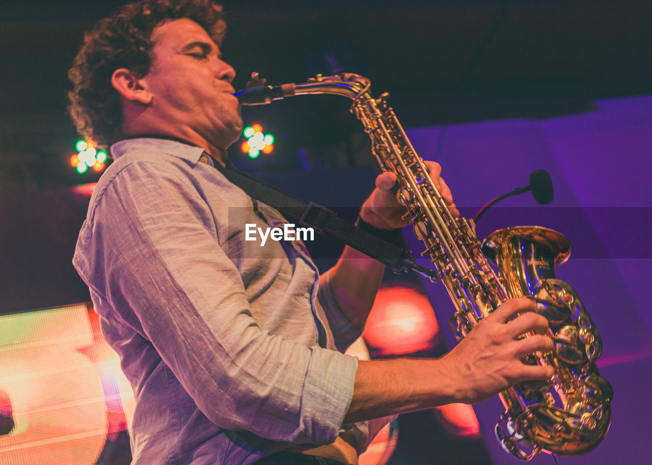 Low angle view of man playing saxophone at music concert