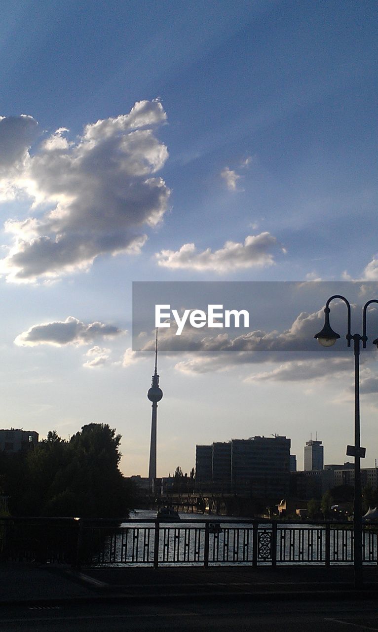 River in city by silhouette fernsehturm against sky