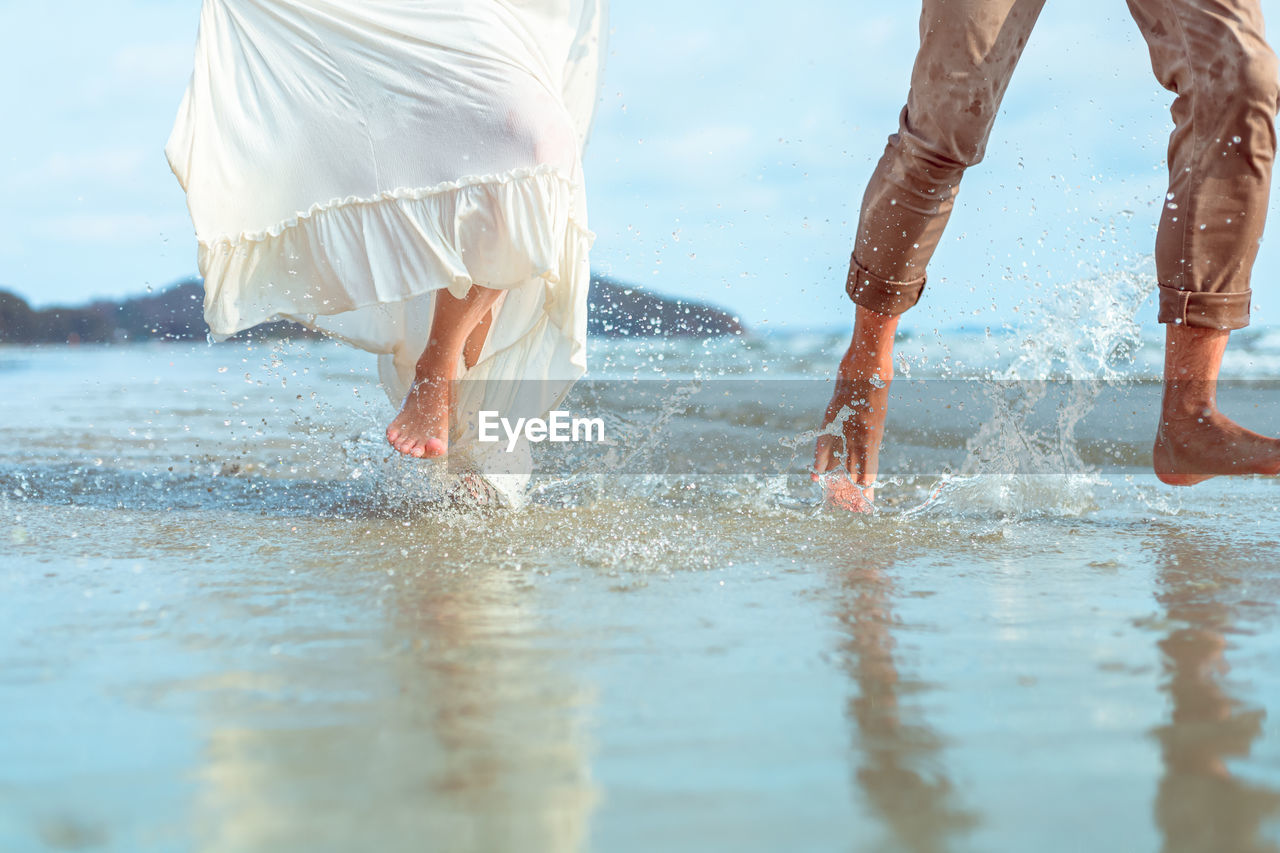 Low section of couple running in sea