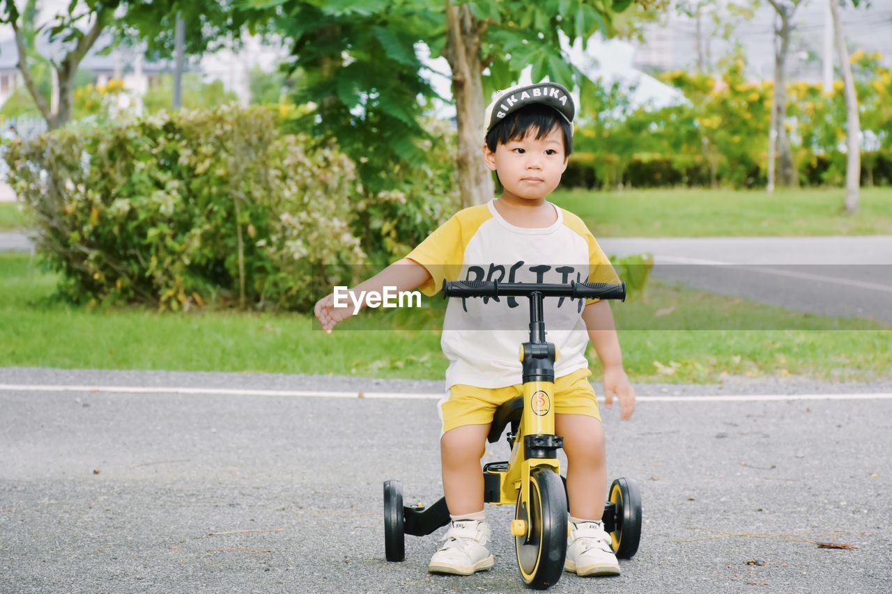 Portrait of boy riding push scooter on road