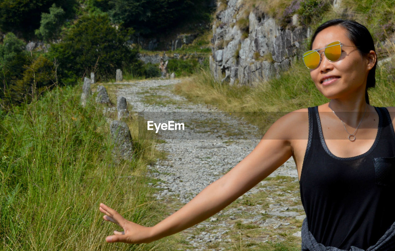 Smiling young woman wearing sunglasses on field