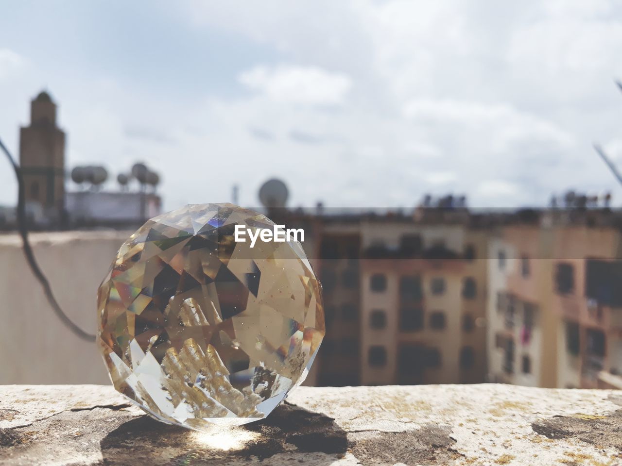 Close-up of crystal ball on land against sky in city