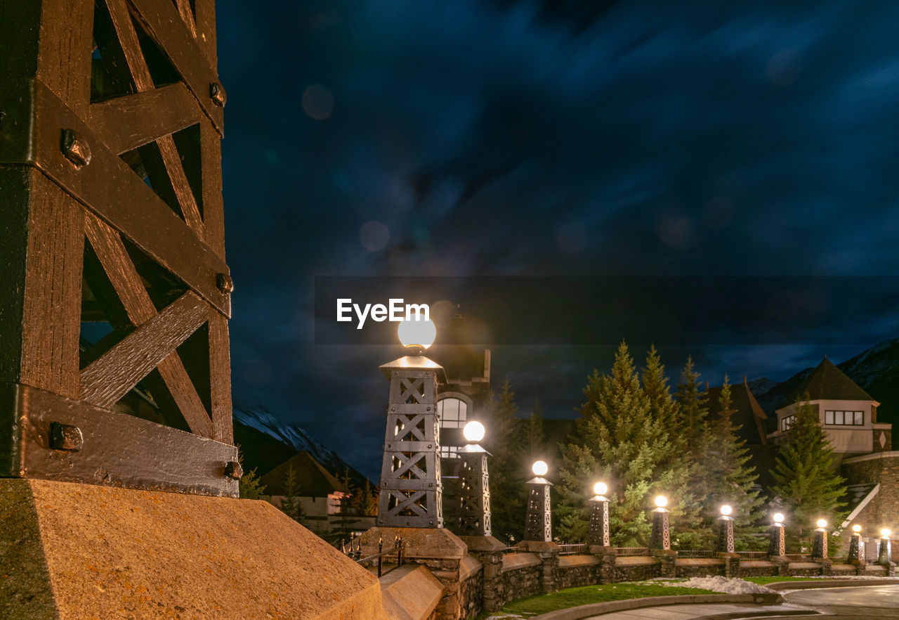 ILLUMINATED STREET AMIDST BUILDINGS AT NIGHT