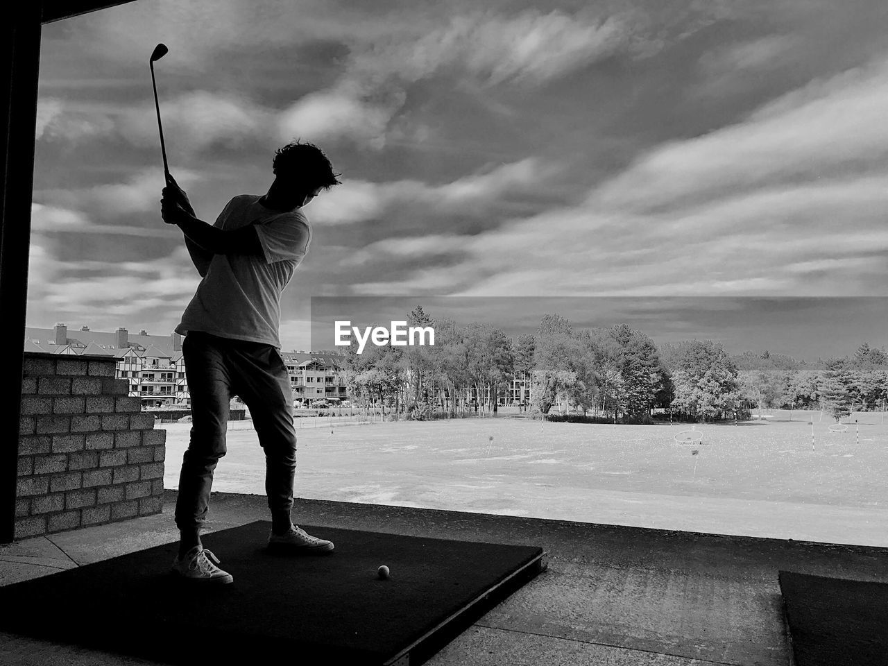 Full length of man playing golf against cloudy sky