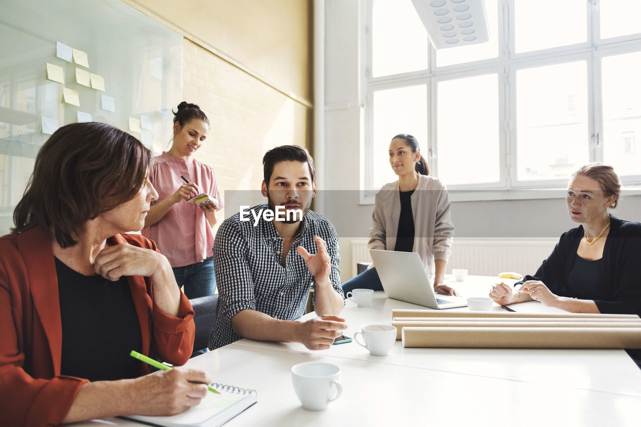 Businessman explaining new project to female colleagues at conference table