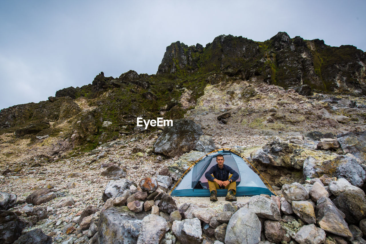 Full length of man sitting in tent on mountain