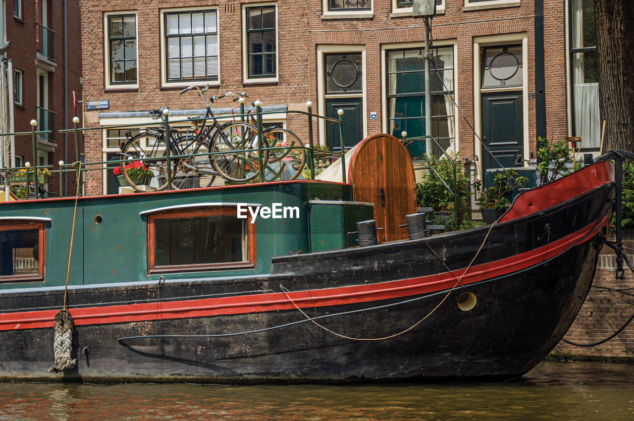 Big boat moored at side of tree-lined canal in amsterdam. the netherland capital full of canals.