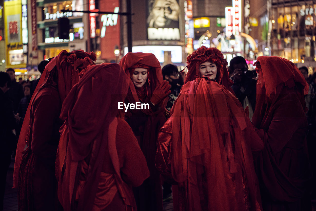 GROUP OF PEOPLE WALKING IN FRONT OF BUILDING AT NIGHT