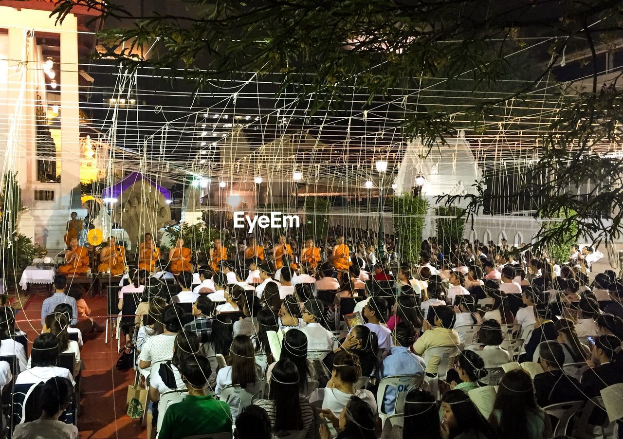 People connected with threads during buddhist ritual at night