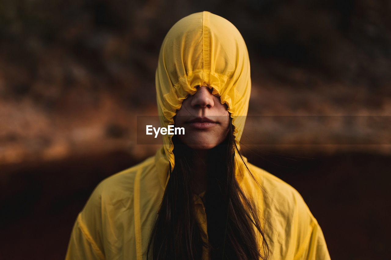 Young lady in yellow raincoat strolling in nature