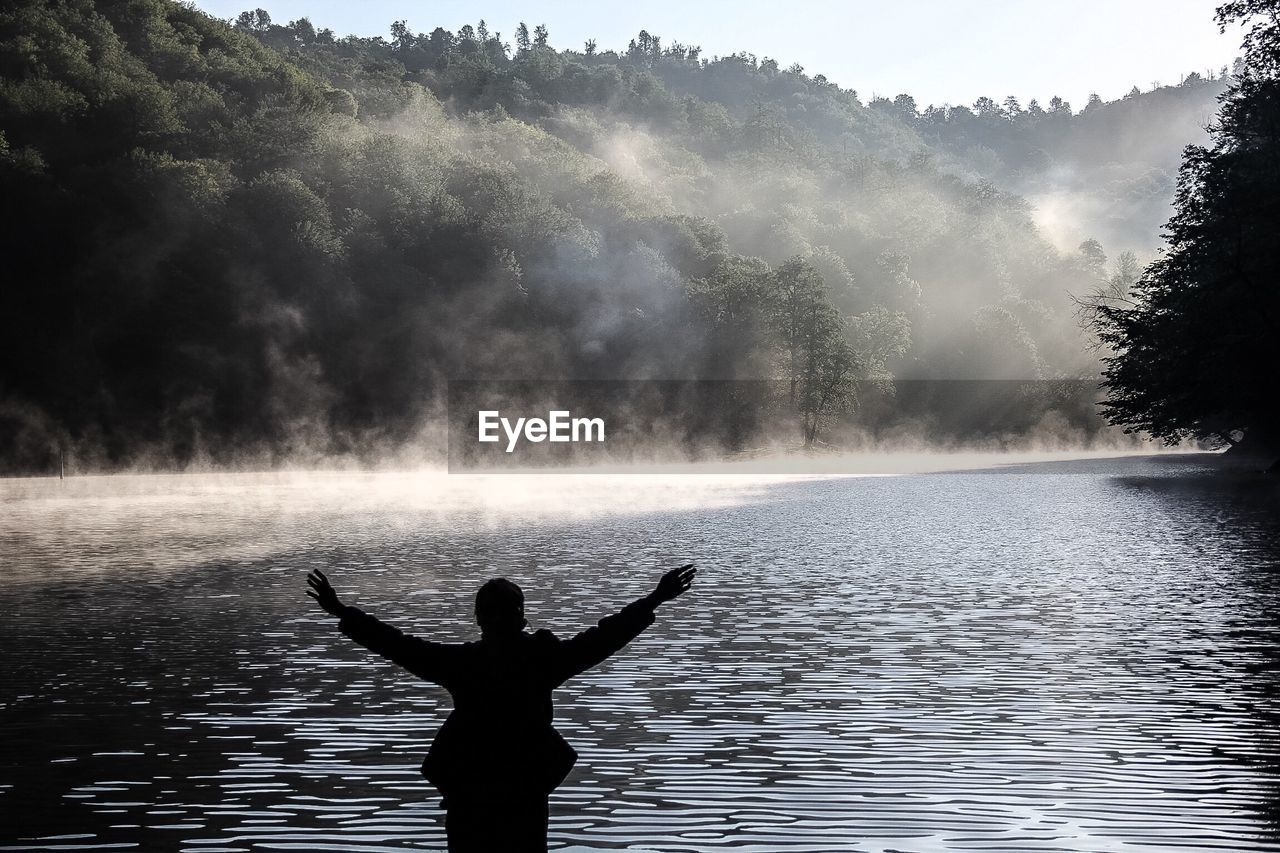 Rear view of woman overlooking calm lake