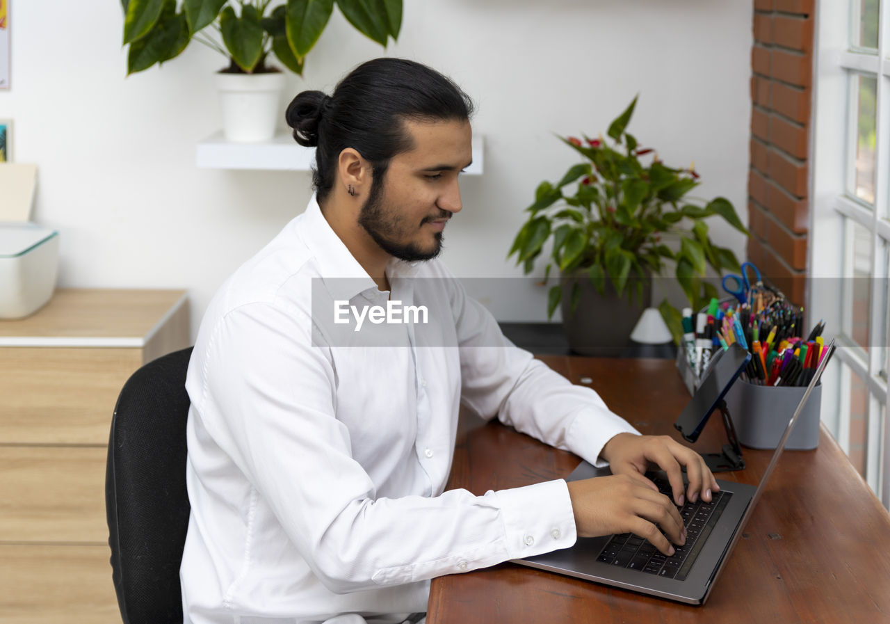 YOUNG MAN USING MOBILE PHONE AT HOME