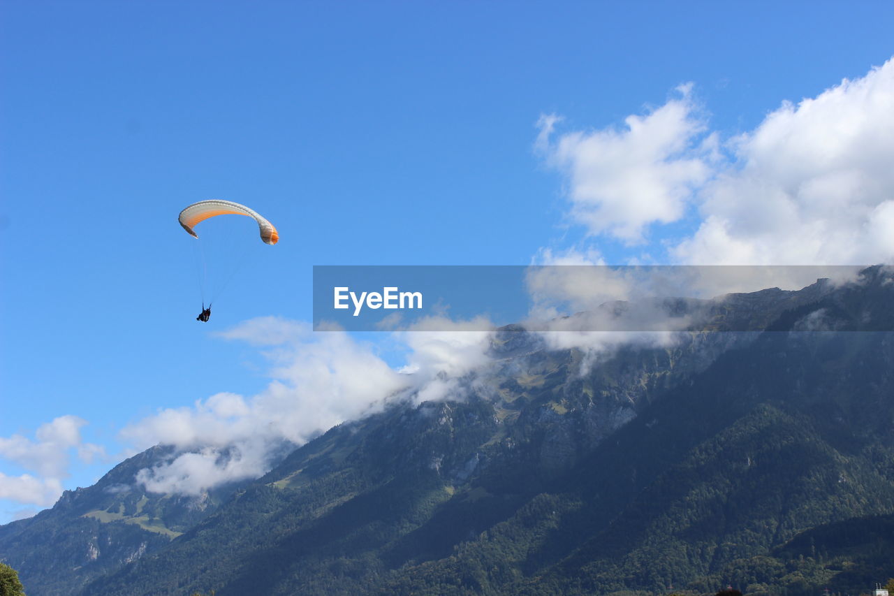 LOW ANGLE VIEW OF PARAGLIDING AGAINST MOUNTAINS