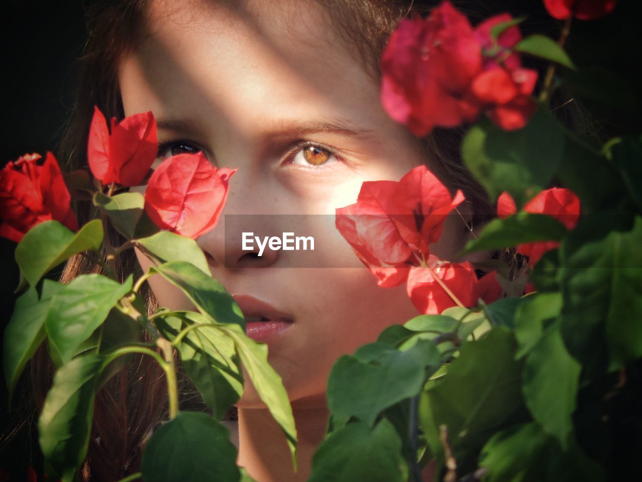 Close-up portrait of girl with red flowers