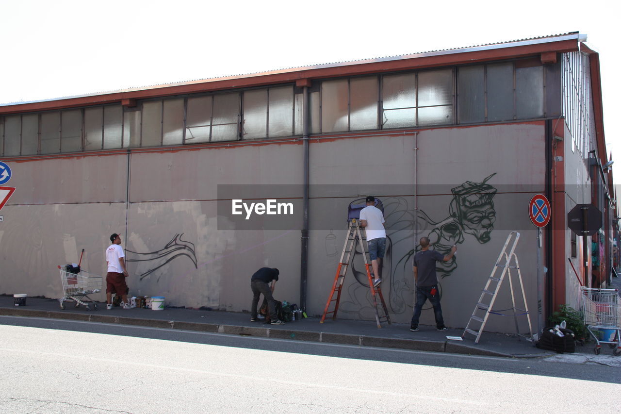 Men painting on building wall