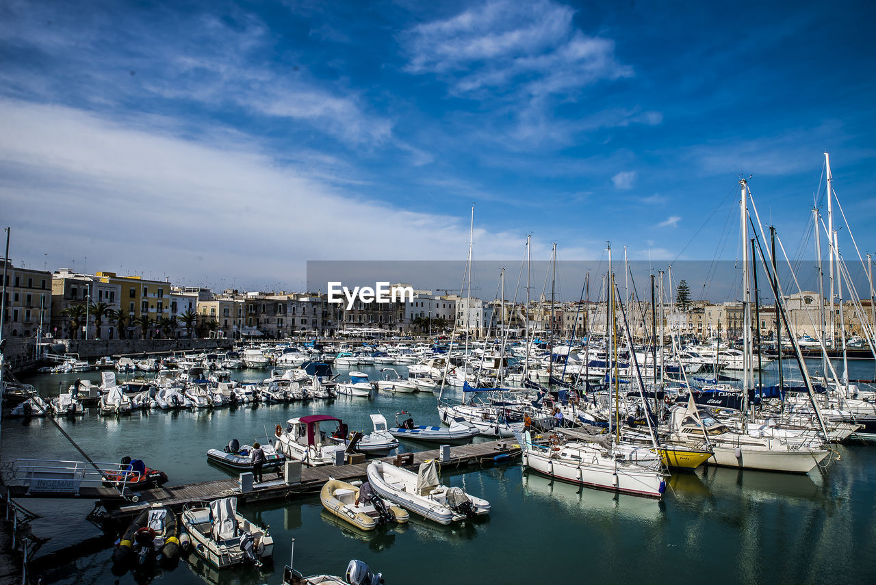 Sailboats moored at harbor against sky