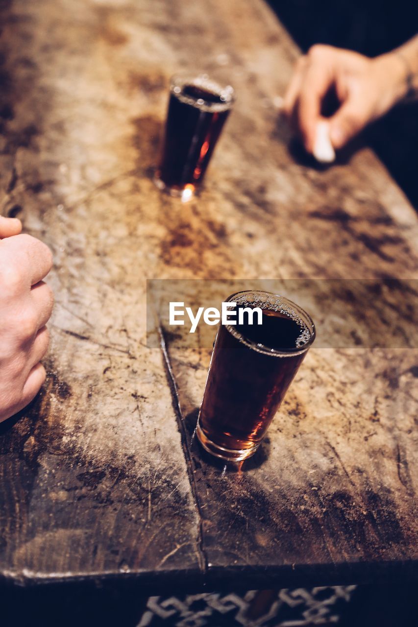 HIGH ANGLE VIEW OF HAND HOLDING GLASS OF TABLE