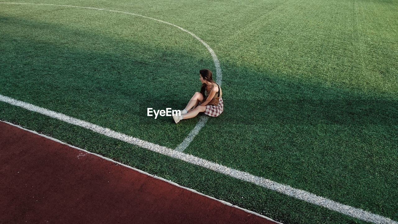 Young woman sitting on sport field