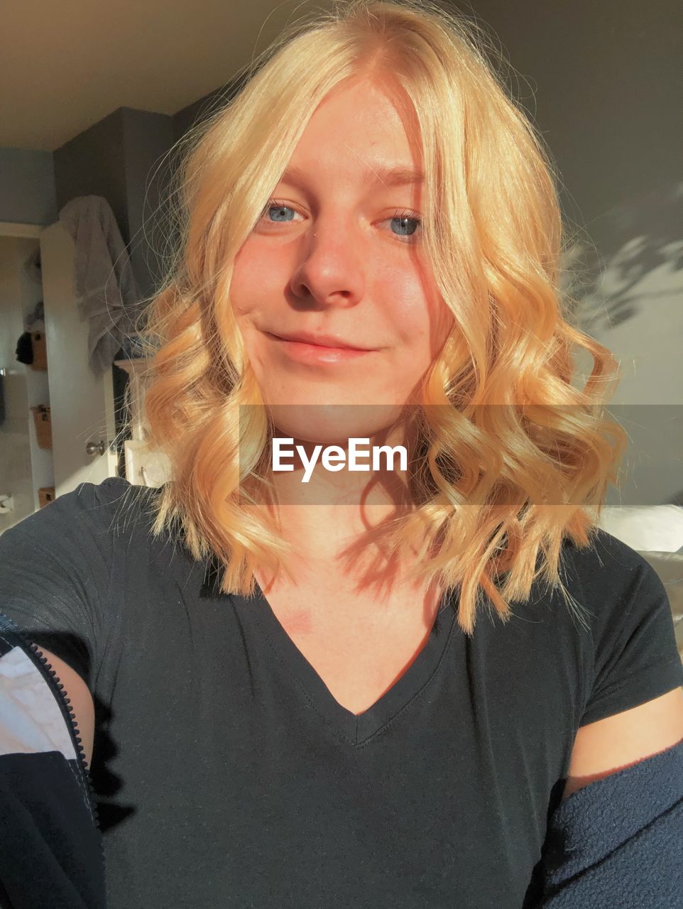 PORTRAIT OF A SMILING YOUNG WOMAN AT HOME