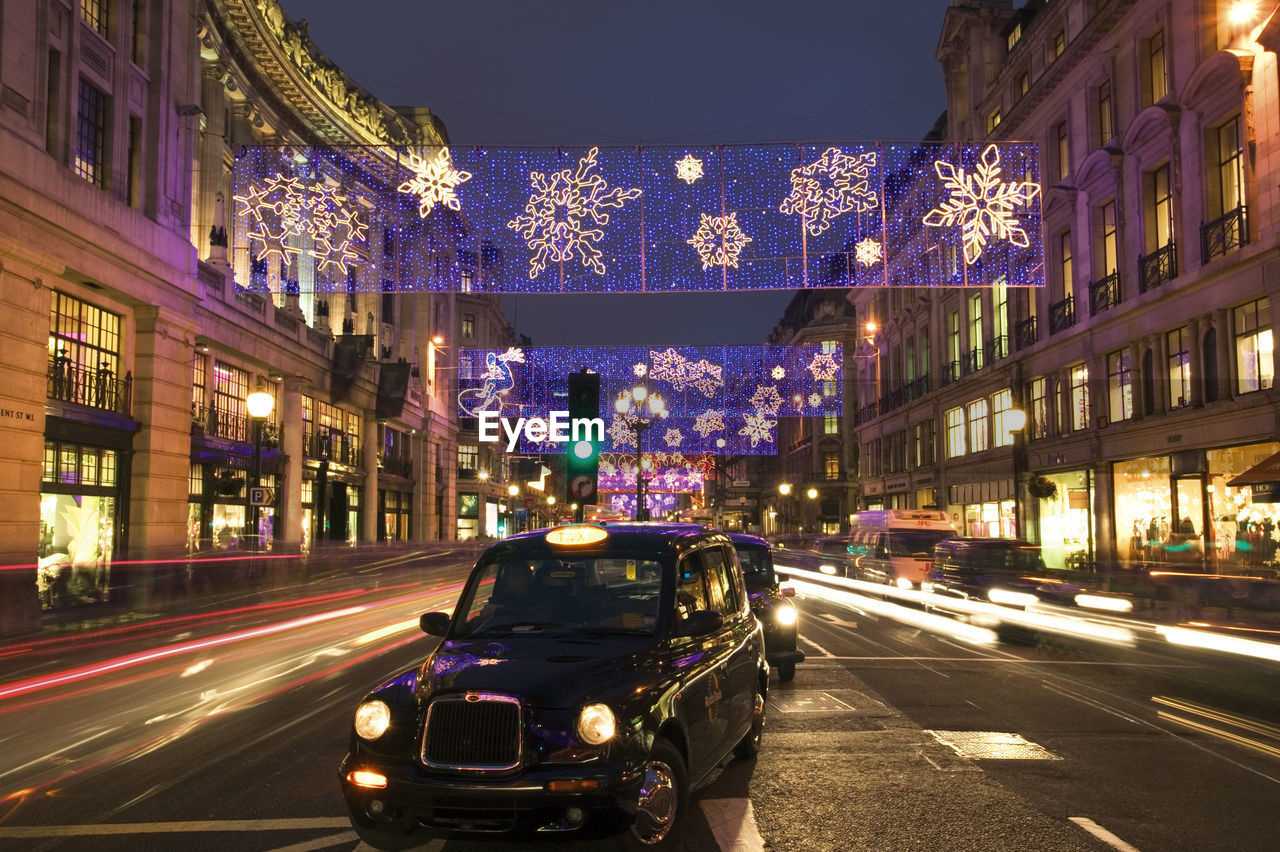 TRAFFIC ON CITY STREET BY ILLUMINATED BUILDINGS