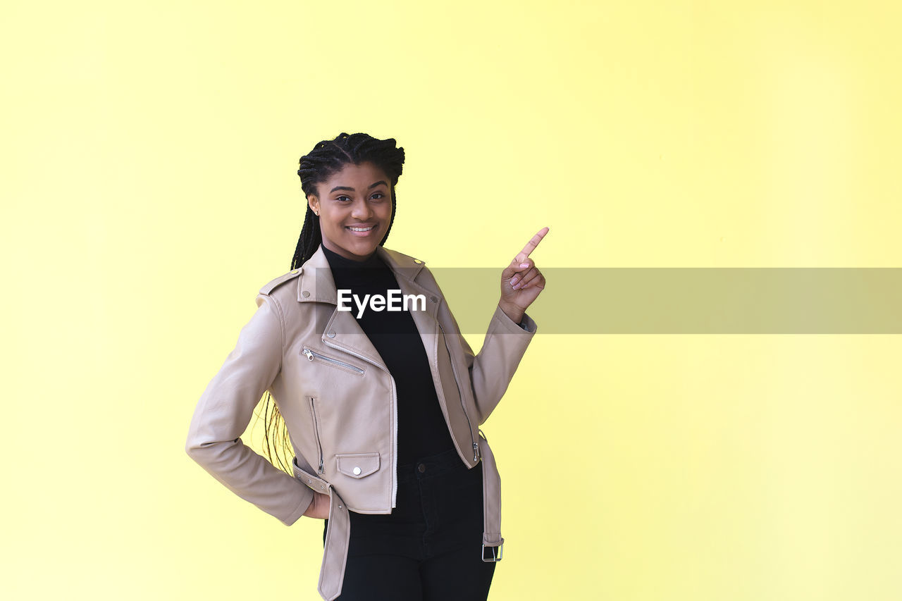 PORTRAIT OF YOUNG WOMAN AGAINST GRAY BACKGROUND