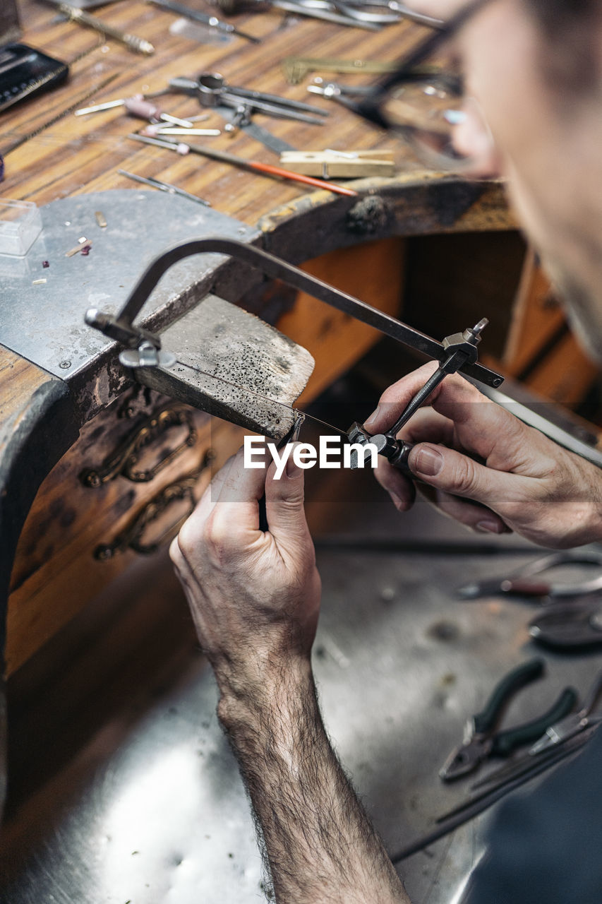 Stock photo of concentrated man working with tools in artisan workshop