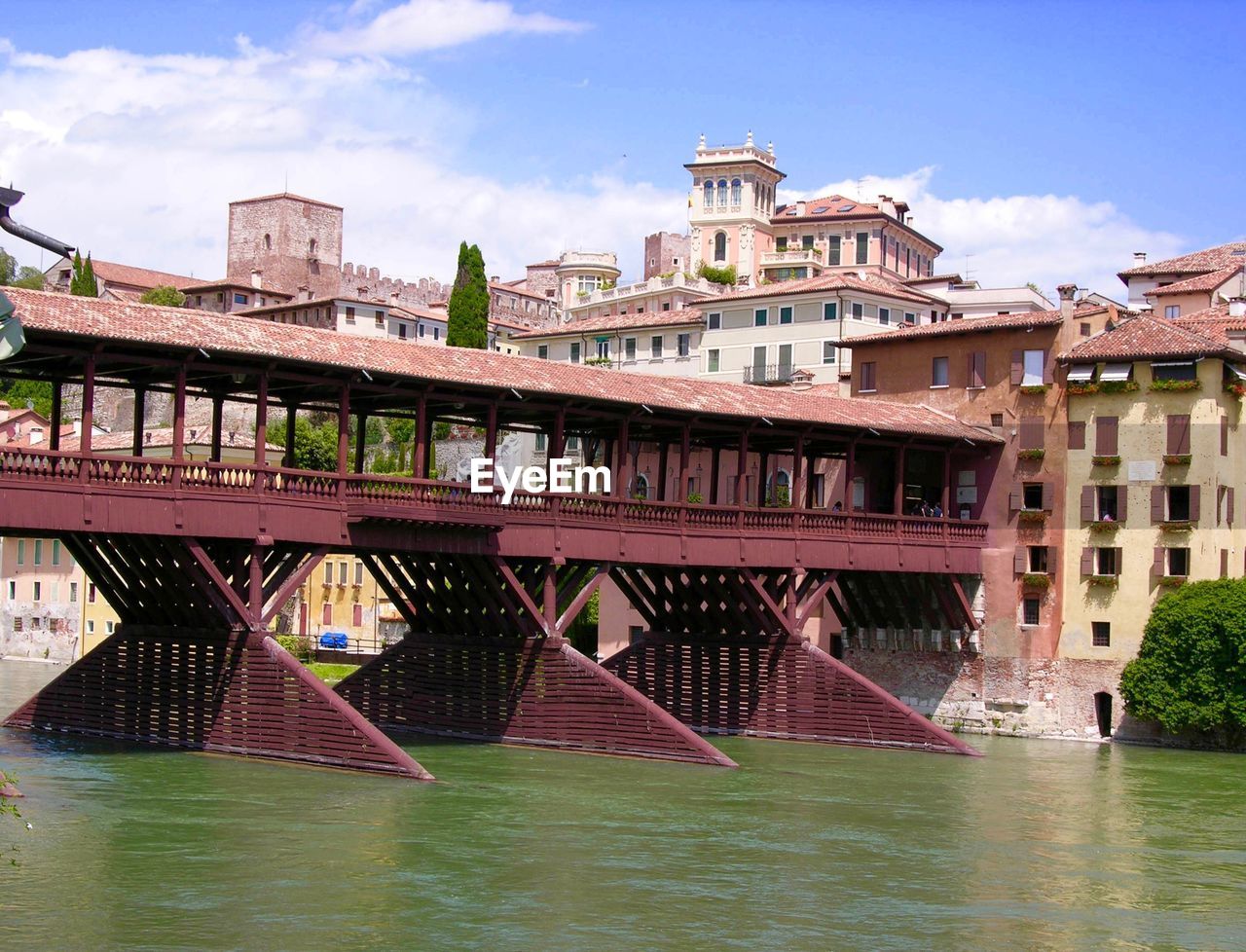 Bridge over river by houses against sky