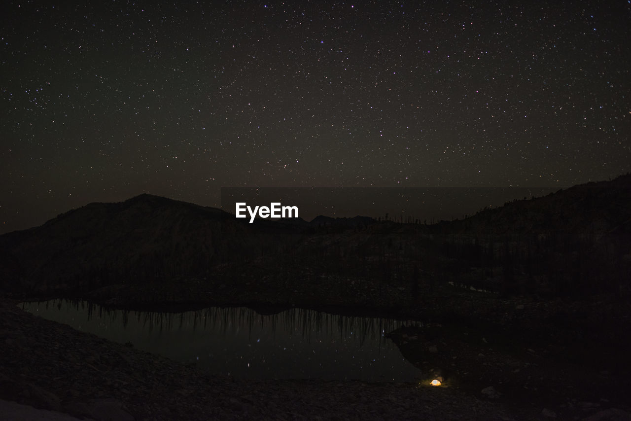 Scenic view of lake and mountains against sky at night