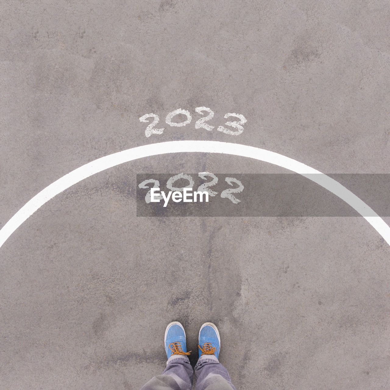 2022 and 2023, text on asphalt ground, feet and shoes on floor, personal perspective footsie concept